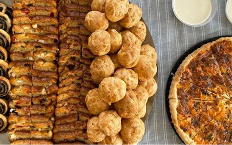 Vue de dessus d'une table de cocktail dînatoire préparé par Les Régalades de Delphine, traiteur à Paris et en Ile-de-France. Sur la table : tranches de cakes salés, gougères et parts de tartes salées.