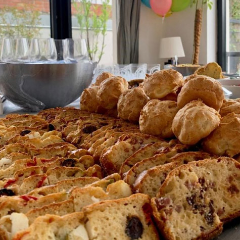 Vue de près sur une table d'un cocktail dînatoire préparé par Les Régalades de Delphine. Sur la table : tranches de cakes salés et gougères au fromage.