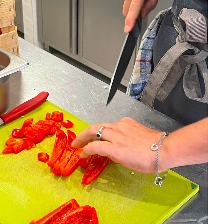 Traiteur à Paris 20 découpant un poivron en lamelles dans sa cuisine professionnelle.