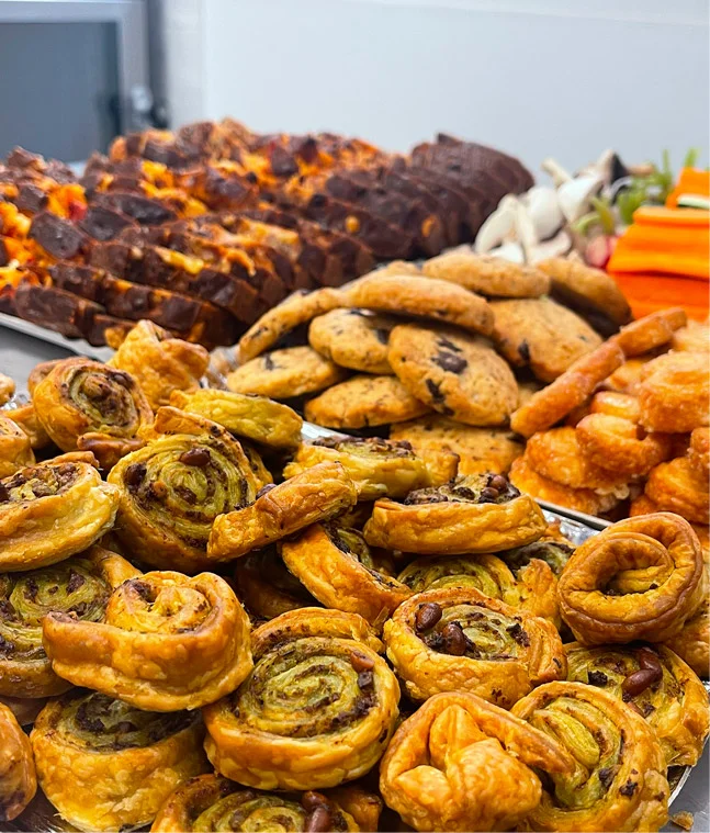 Aperçu d'un buffet apéritif préparé par Les Régalades de Delphine et composé de roulés feuilletés, de crudités, de tranches de cake salés, de cookies et palmiers faits maison.